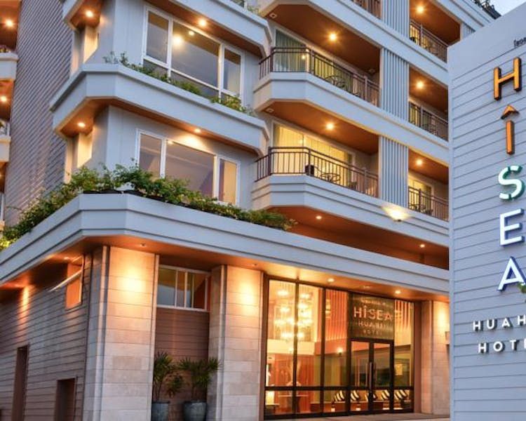Evening view of the Hisea Hua Hin Hotel facade and main entrance sign, showcasing the contemporary architectural design and private guest balconies.